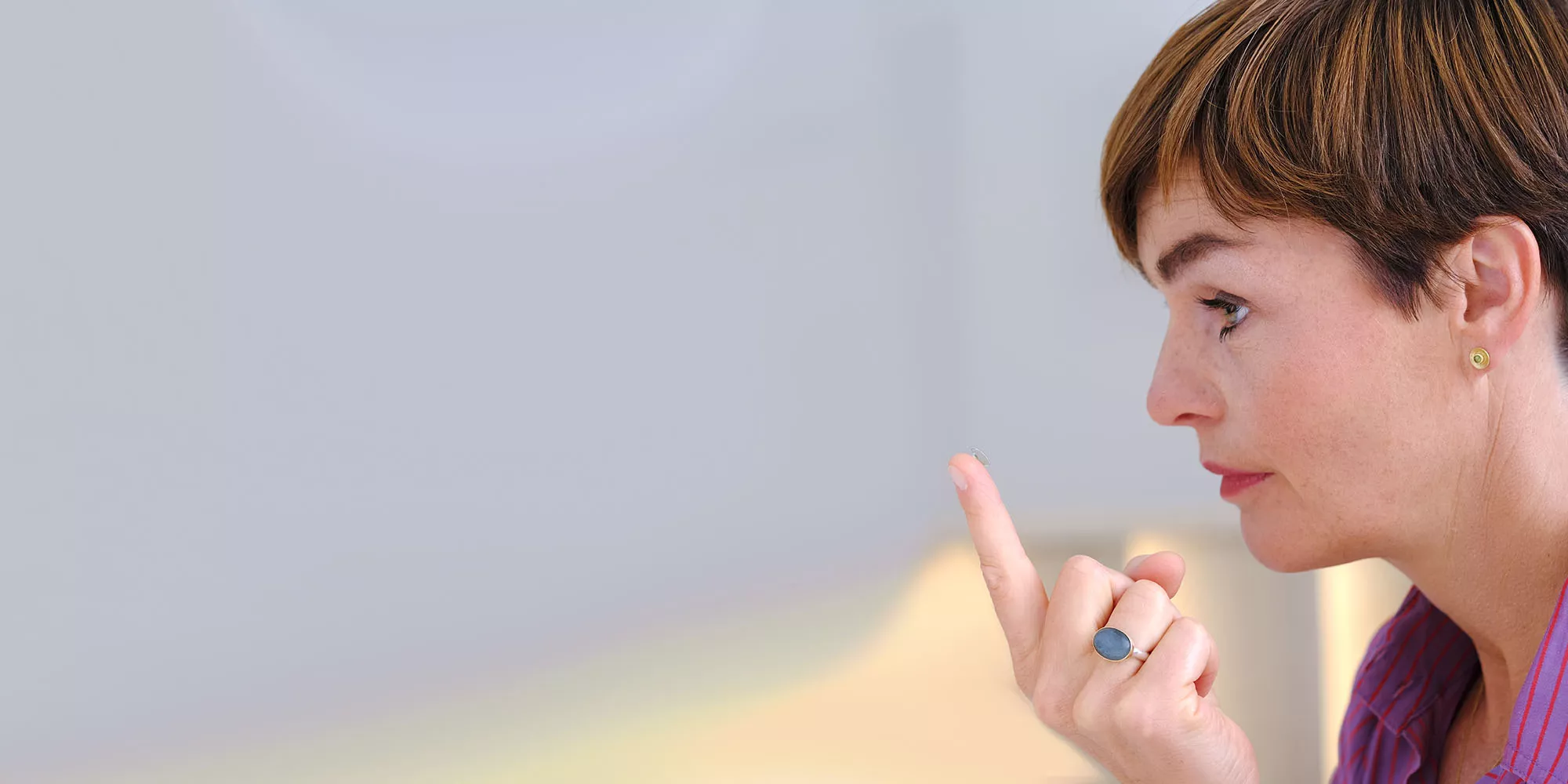 Frau mit Kontaktlinse auf der Fingerspitze