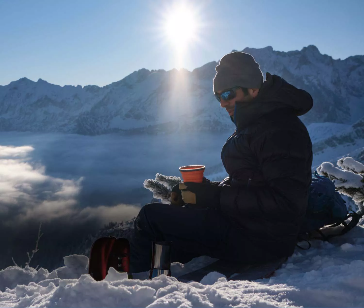 Mann mit Sportbrille auf einem schneebedeckten Gipfel